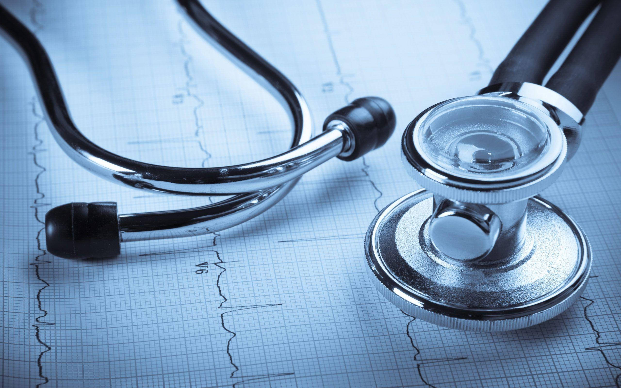 Stethoscope 桌布 壁紙 — 一個閃亮的聽診器放在顯示心跳線的藍色醫療圖表紙上。