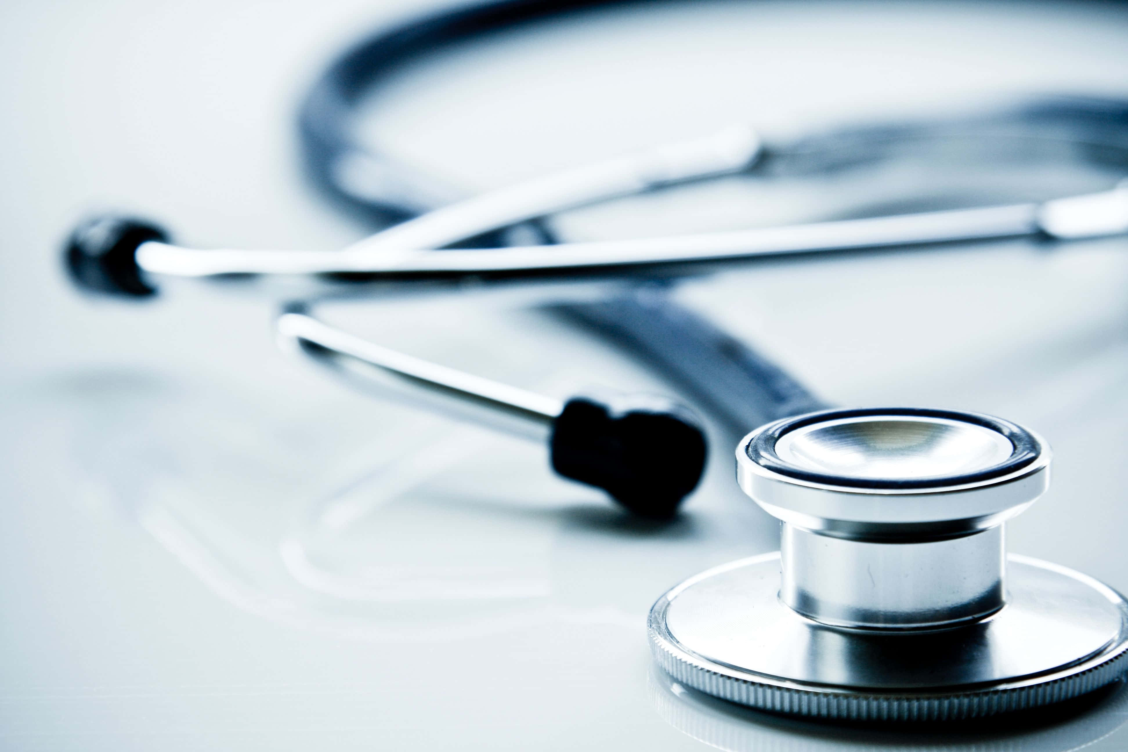 Stethoscope 桌布 壁紙 — 一個閃亮的聽診器特寫，放置在反射性白色表面上，景深較淺。