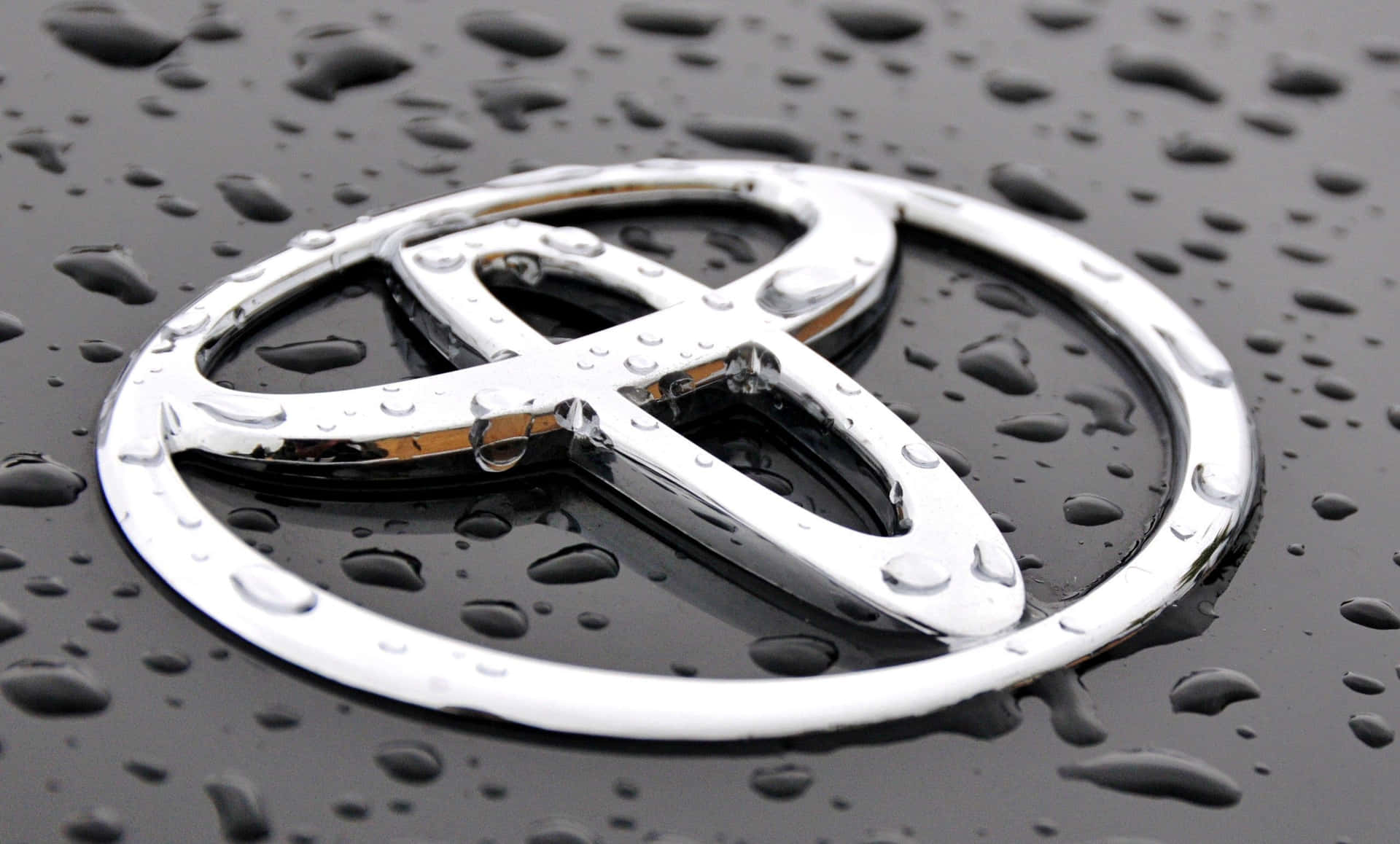鍍鉻豐田標誌在潮濕的黑色引擎蓋上，帶有雨滴。 — Toyota Supra Mk4 壁紙