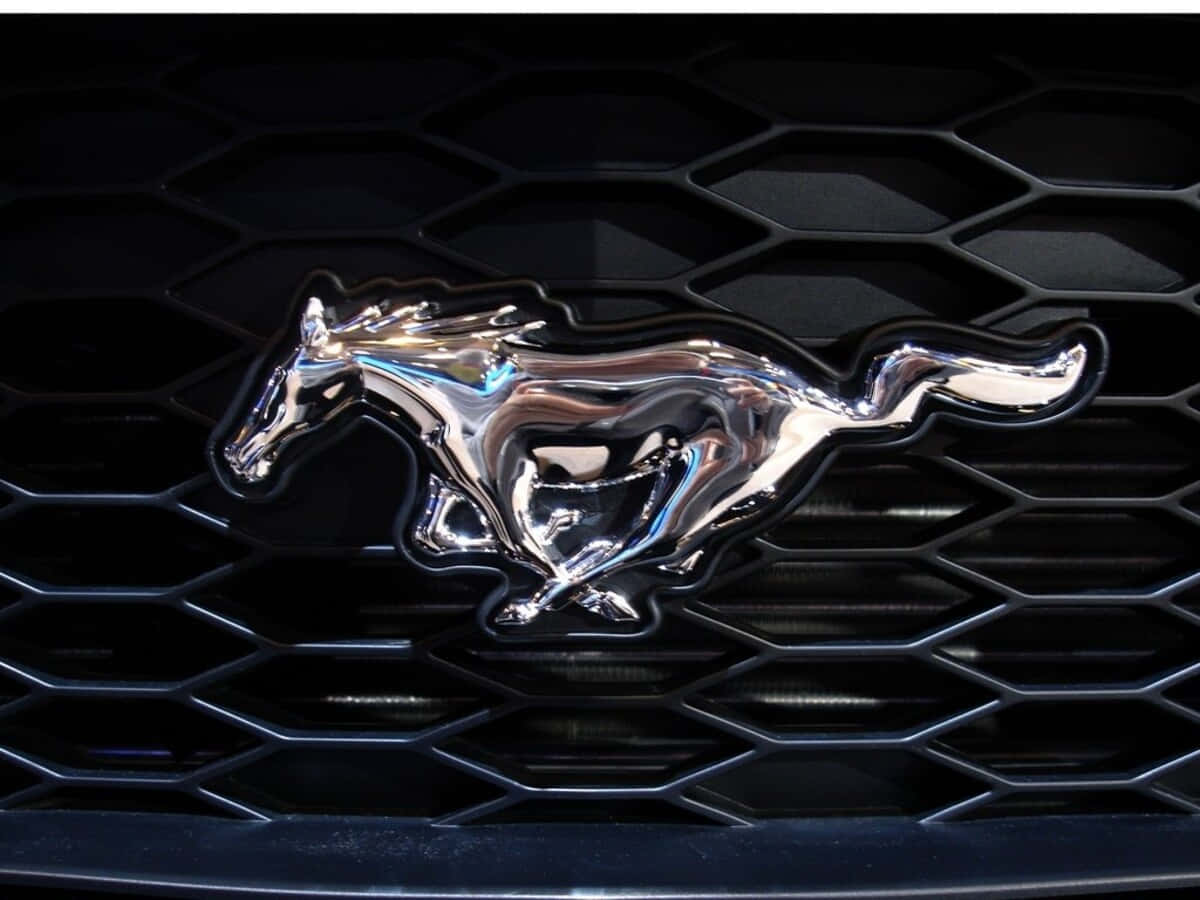 Ford Logo 桌布 壁紙 — 一個閃亮的鍍鉻野馬馬標誌，位於黑色六邊形汽車格柵中央，帶有銳利的燈光反射。