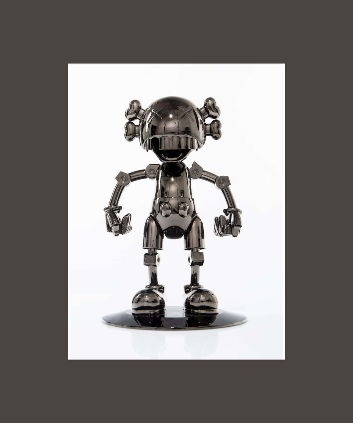 Kaws Figures 桌布 壁紙 — 一個閃亮的黑色鉻合金機器人公仔，頭部像骷髏，四肢有關節，站在一個反射底座上，背景是純白色。