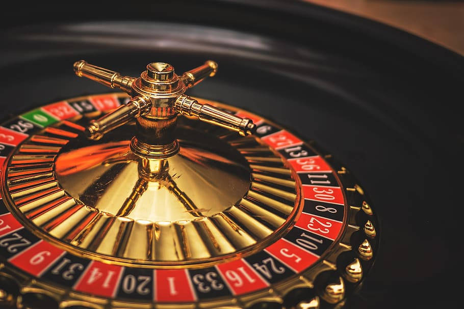 game 桌布 壁紙 — 一個閃亮金色輪盤的近距離特寫，帶有紅色和黑色編號的格子，在賭場中旋轉。