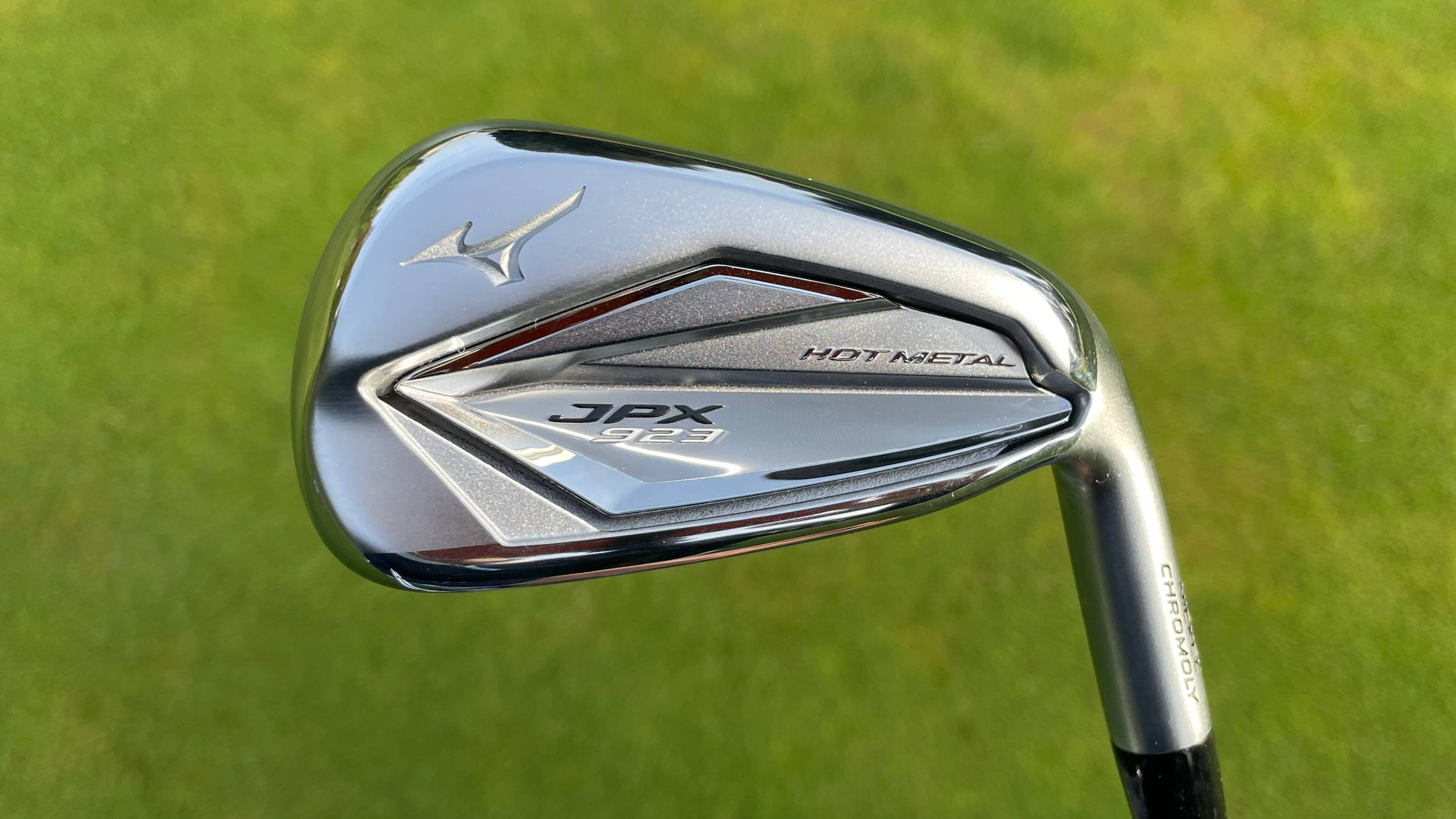 高爾夫 桌布 壁紙 — 一個閃亮銀色Mizuno JPX 912 Hot Metal高爾夫鐵桿的特寫，放在充滿活力的綠色草地上。