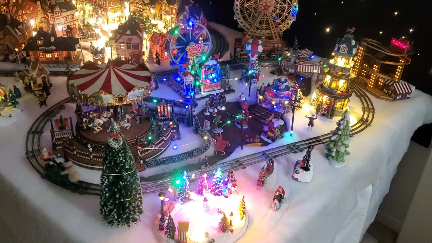 Christmas Village 桌布 壁紙 — 一個閃閃發光的微型冬日仙境，有發光的節日燈飾、白雪覆蓋的樹木和星空下的旋轉木馬。