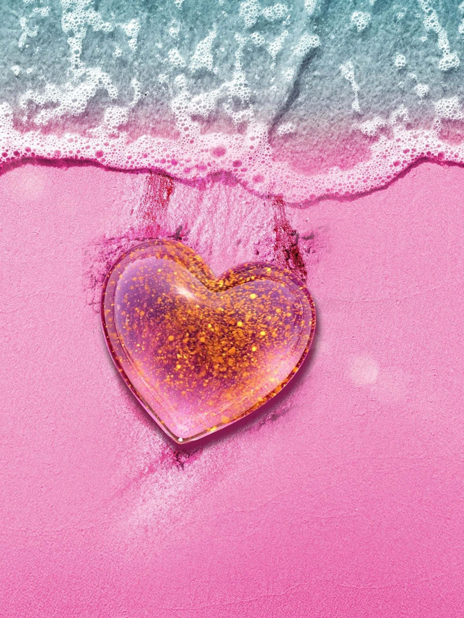 Glitter Pink Hearts 桌布 壁紙 — 一個閃閃發光的心形物體放在鮮豔的粉紅色沙子上，土耳其藍色的海浪輕輕拍打著它的邊緣。