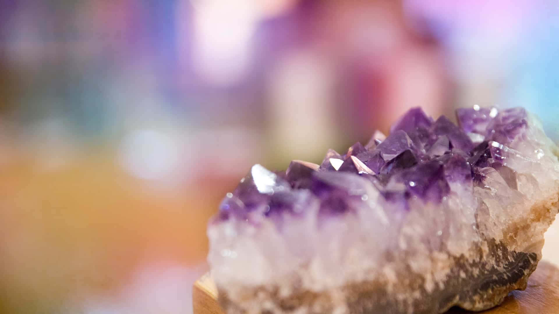 水晶 桌布 壁紙 — 一個閃閃發光的紫水晶晶簇特寫，帶有銳利的紫色刻面，放置在木質底座上，背景柔和模糊。