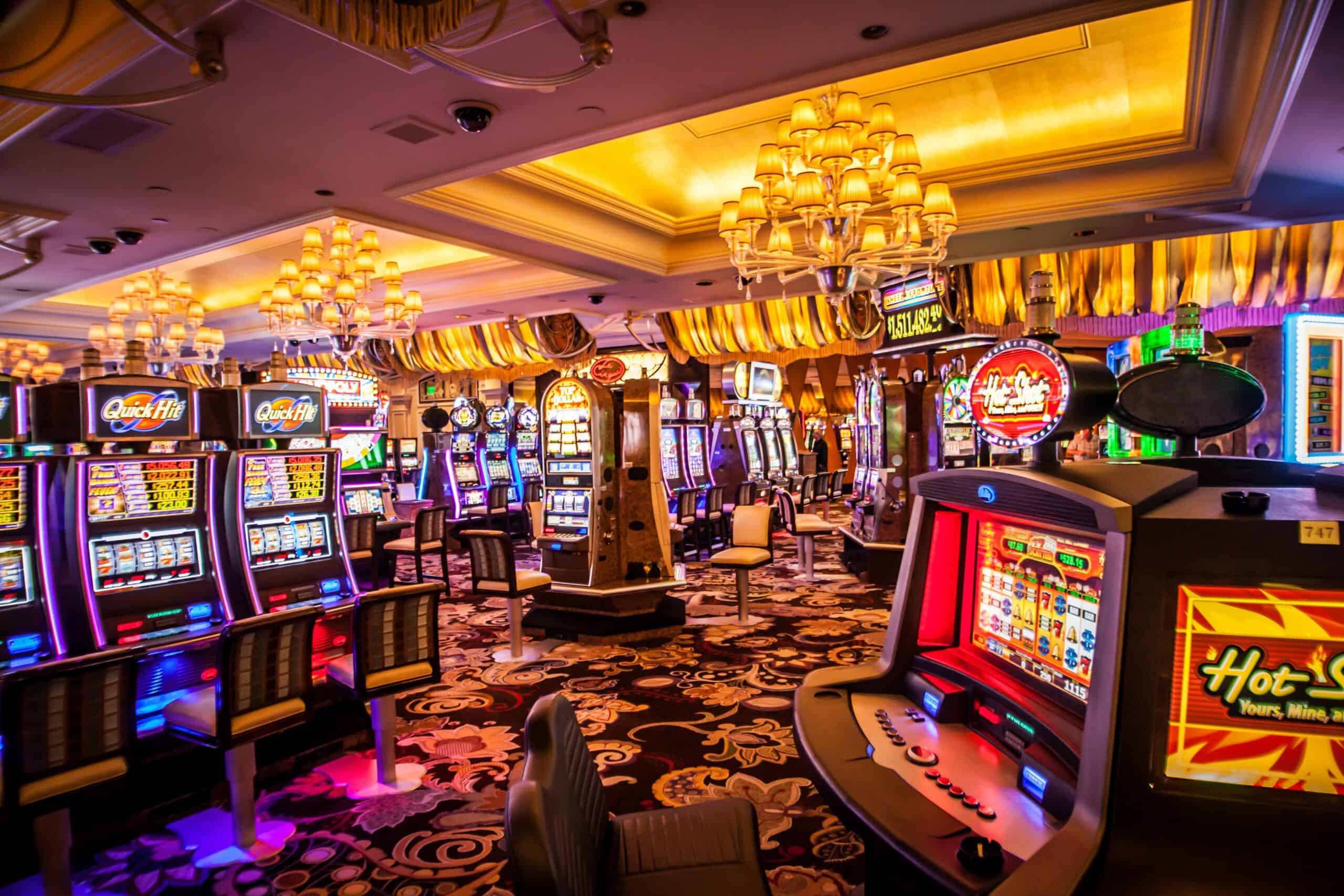 arcade 桌布 壁紙 — 一個閃閃發光的賭場地板，充滿了在華麗吊燈和圖案地毯下發光的老虎機。