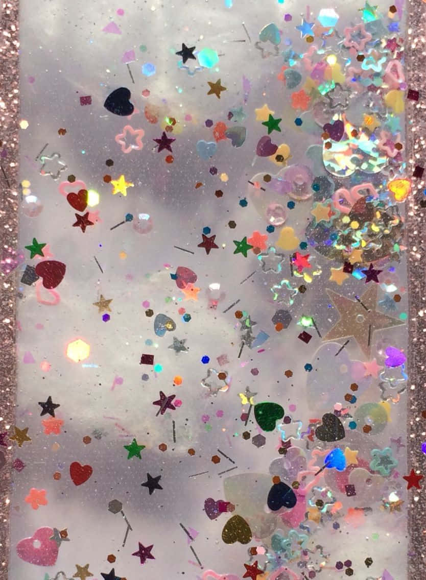 Sparkle Aesthetic 桌布 壁紙 — 一個閃閃發光的透明容器，裡面裝滿了在液體中旋轉的彩色愛心、星星和亮片。