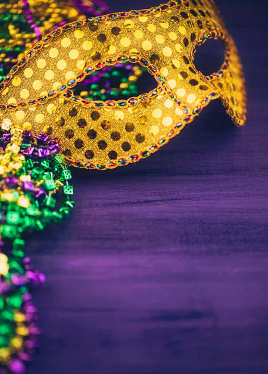 Mask 桌布 壁紙 — 一個閃閃發光的金色圓點狂歡節面具，飾有彩色珠子，放在深紫色木質表面上。