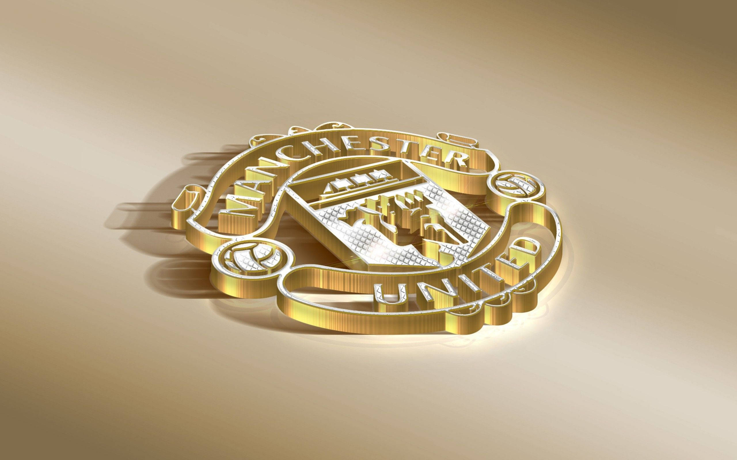 Manchester United Logo 桌布 壁紙 — 一個閃閃發光的金色曼聯會徽，放置在柔和的漸變背景上，帶有戲劇性的燈光和銳利的陰影。
