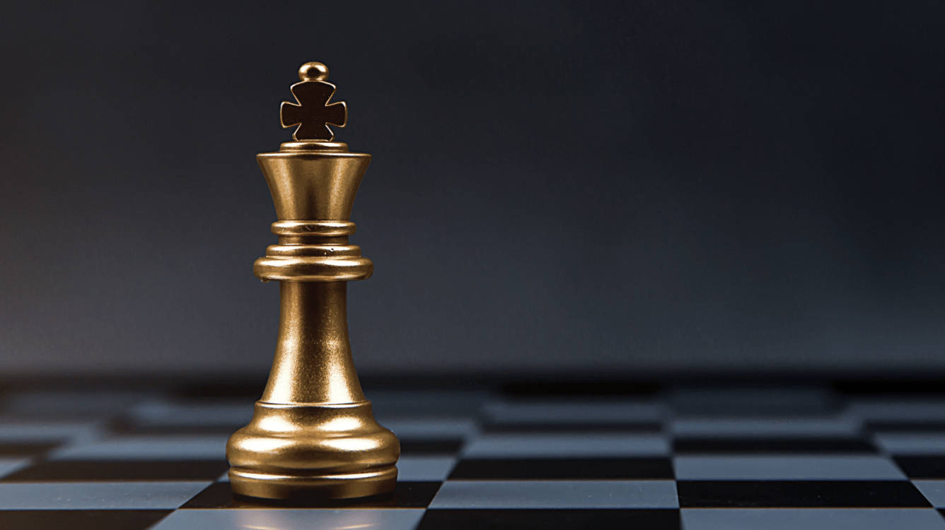 西洋棋 桌布 壁紙 — 一個閃閃發光的金色西洋棋國王高高矗立在棋盤上，背景為深色漸層。