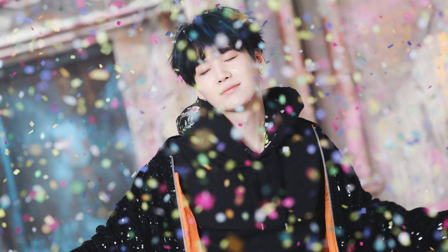 Bts Suga Cute 桌布 壁紙 — 一個閉上眼睛的年輕男子，在五彩紙屑如雨般落在他周圍時，平靜地微笑。