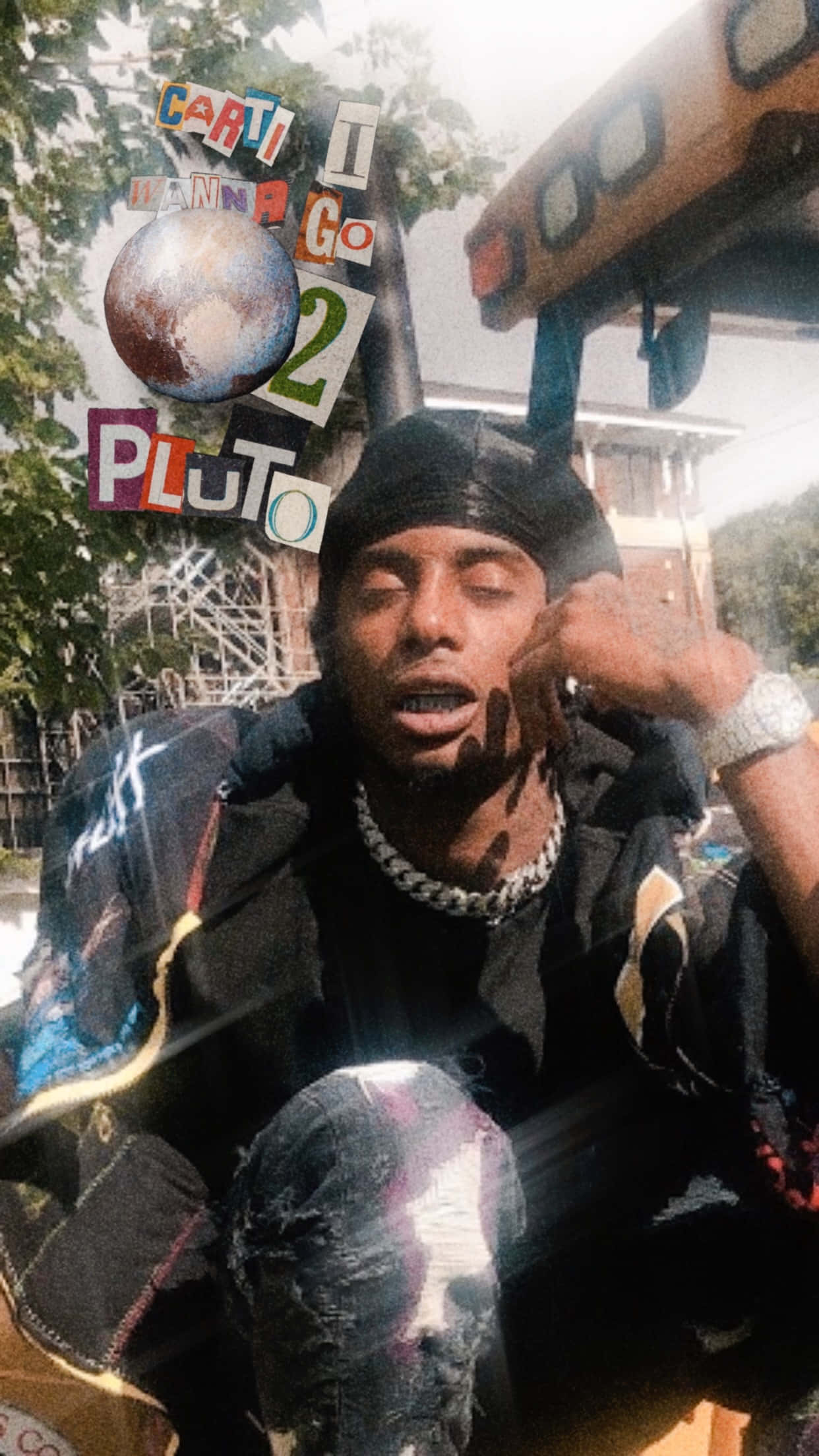 Playboi Carti iPhone 桌布 壁紙 — 一個閉著眼睛、戴著鏈條項鍊的男人坐在拼貼元素中，包括一個地球儀和「PLUTO」文字，背景是明亮的戶外場景。