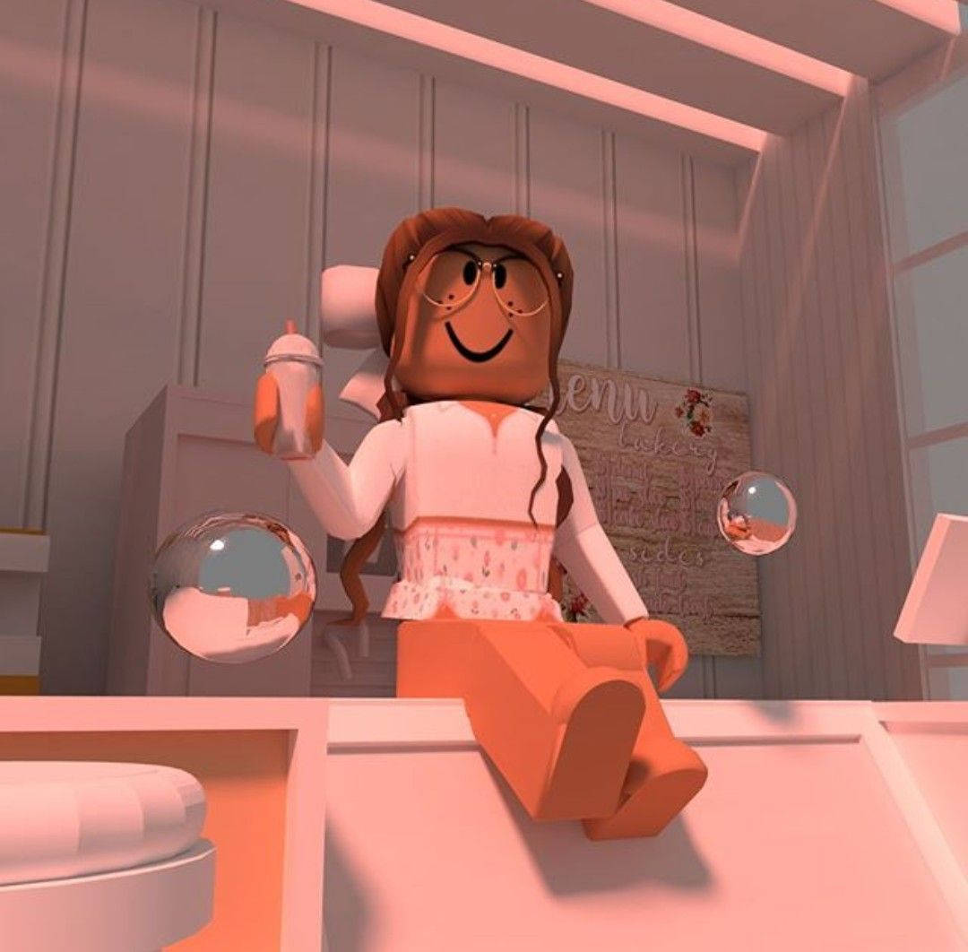 Roblox 桌布 壁紙 — 一個開心的 Roblox 角色，棕色頭髮戴眼鏡，坐在粉紅色櫃檯上，拿著飲料，被反光球體包圍在溫暖照明的房間裡。