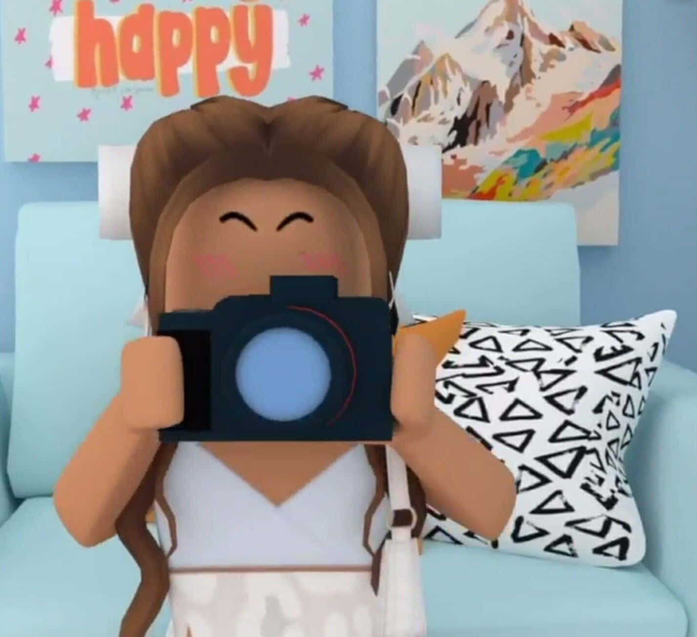 美學 Roblox 女孩 桌布 壁紙 — 一個開心的Roblox頭像，棕色頭髮，拿著相機，坐在淺藍色沙發上，沙發上有圖案枕頭。