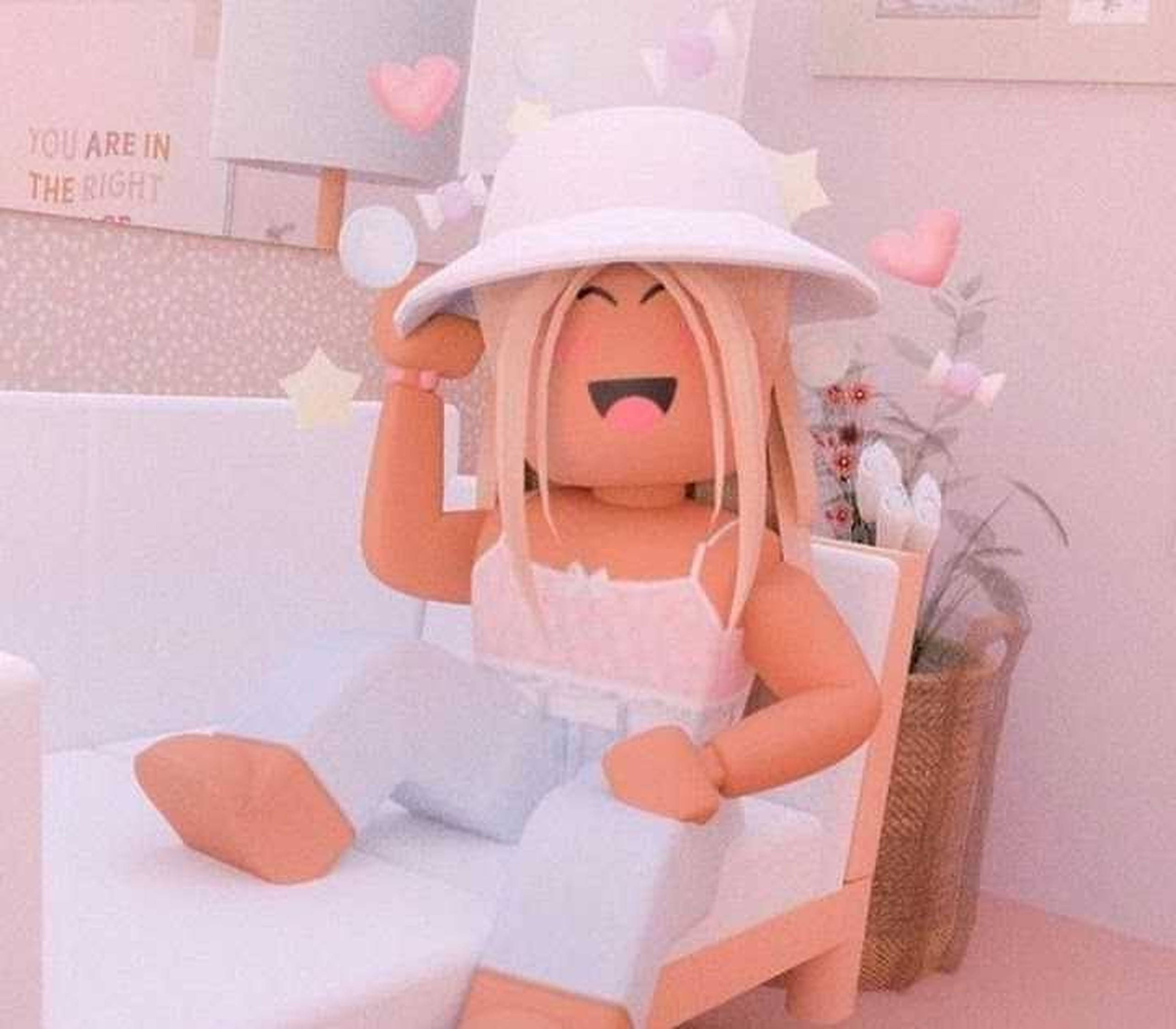 Roblox 女孩 桌布 壁紙 — 一個開心的Roblox頭像，金髮，戴白色帽子，坐在白色椅子上，房間是粉紅色，裝飾有心形和星星。
