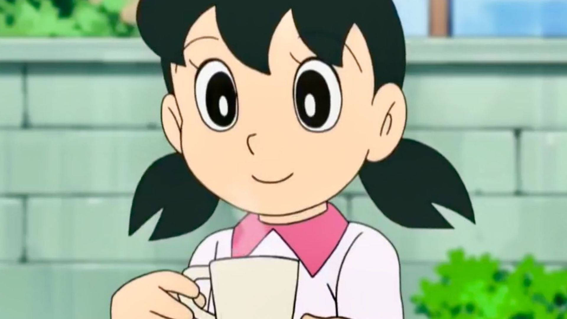 動漫女孩紮雙馬尾，在戶外磚牆旁拿著馬克杯。 — 動漫角色 GIF 壁紙
