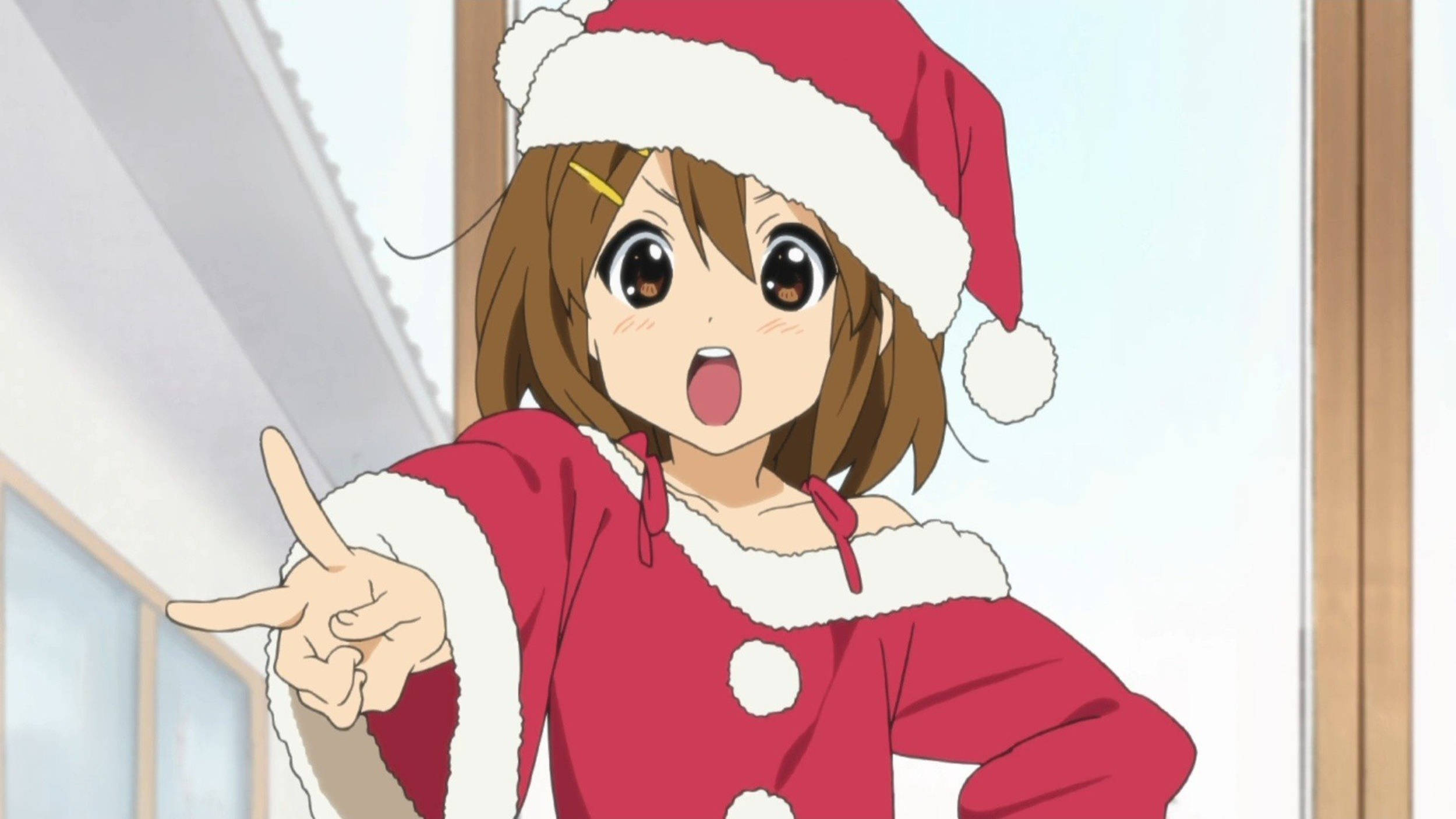 yui hirasawa 桌布 壁紙 — 一個開心的動漫女孩穿著紅色聖誕老人服裝，在室內睜大眼睛興奮地指著。