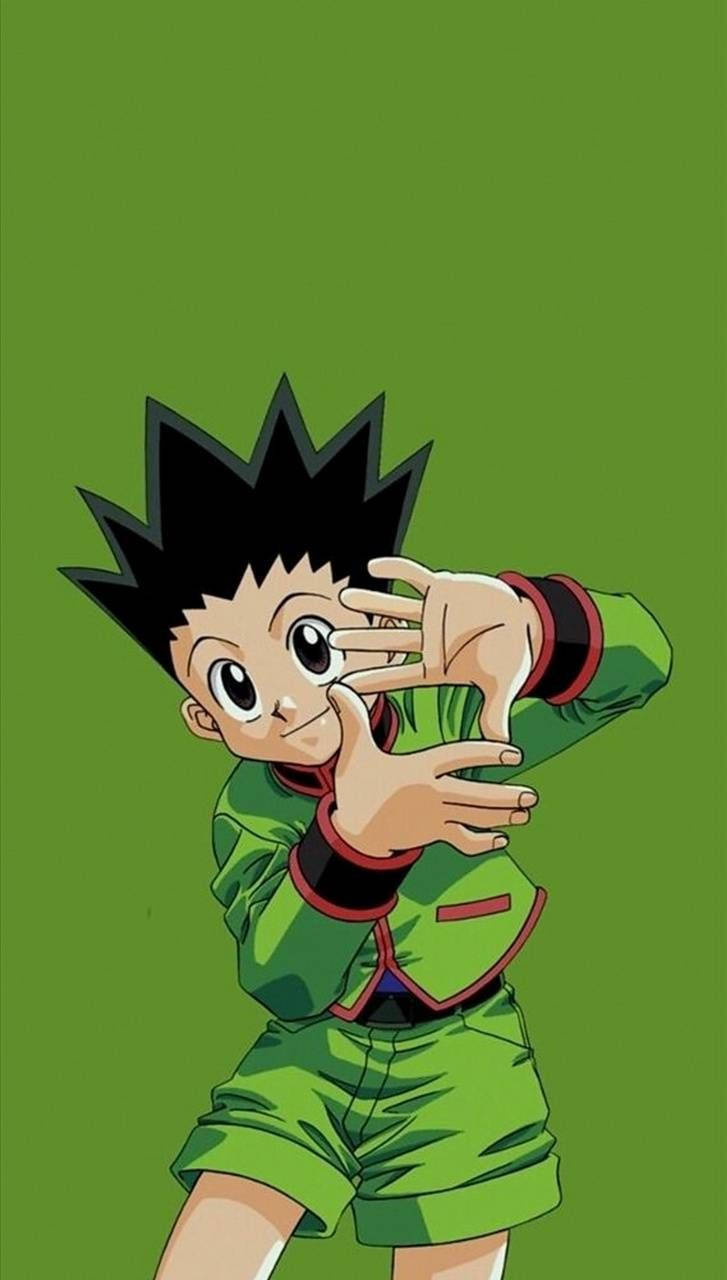 Hunter X Hunter iPhone 桌布 壁紙 — 一個開心的動畫男孩，有著刺刺的黑髮和綠色服裝，在純綠色背景前用雙手頑皮地遮住眼睛。