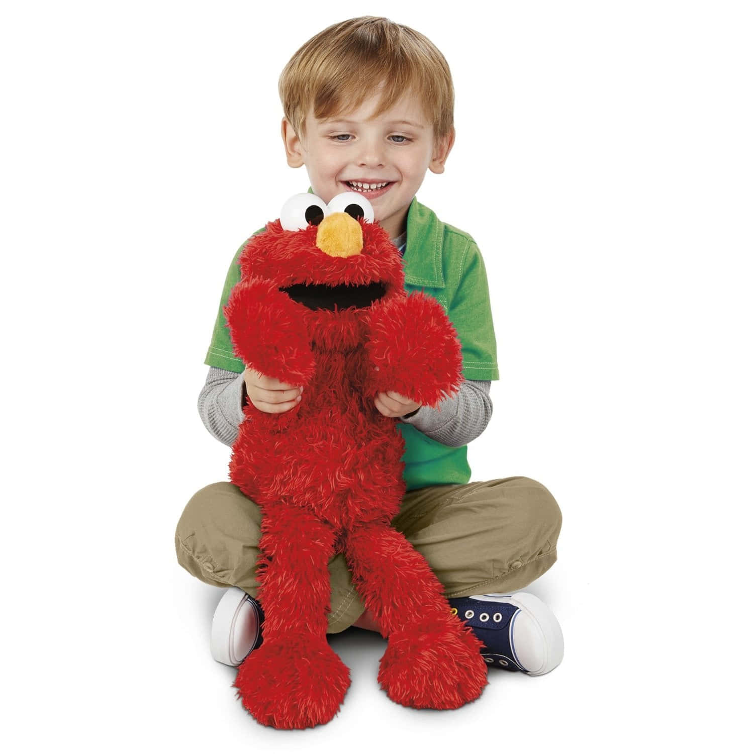 Elmo 桌布 壁紙 — 一個開心的年輕男孩盤腿坐著，在純白色背景前抱著一個大型紅色Elmo毛絨玩具。