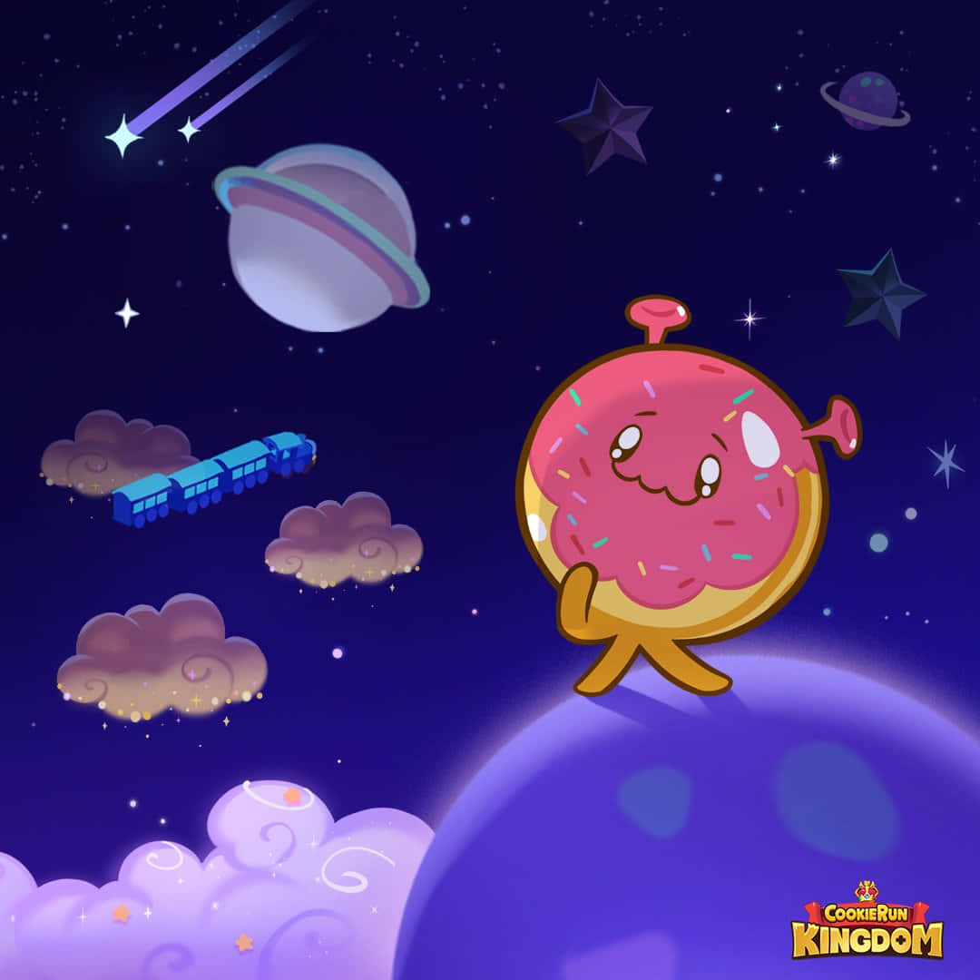 Cartoon Space 桌布 壁紙 — 一個開心的粉紅色糖碎甜甜圈角色站在紫色星球上，在滿天星斗的夜空下，有一輛藍色火車和土星飄過。