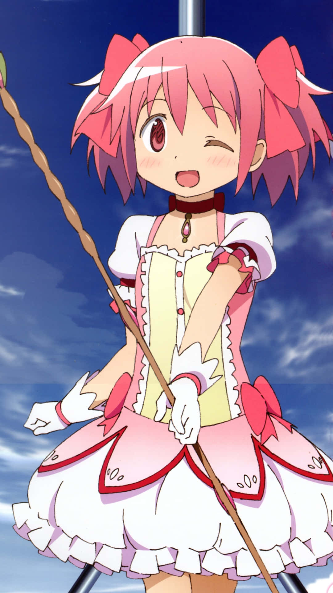 Madoka Magica 桌布 壁紙 — 一個開心的粉紅色頭髮動漫女孩，穿著荷葉邊粉紅和白色連衣裙，在明亮的藍天下拿著法杖眨眼。