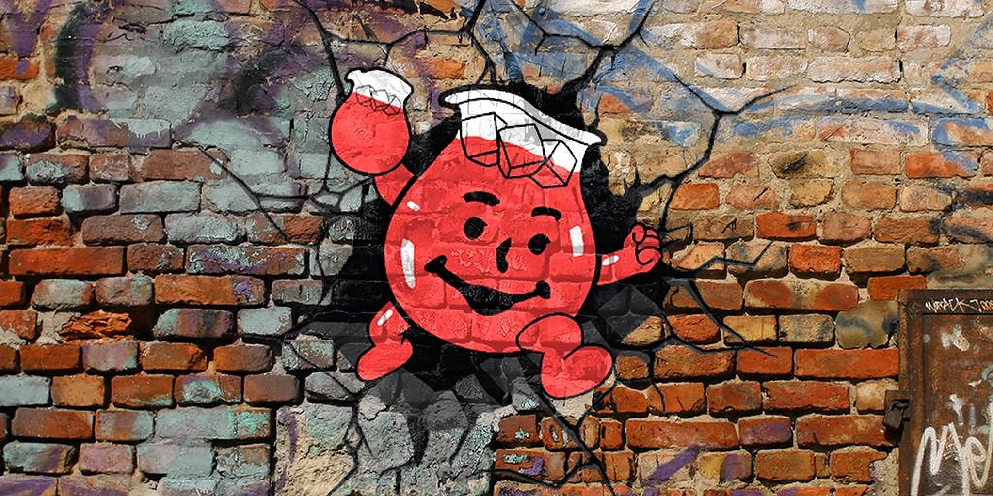 Kool Aid Man 桌布 壁紙 — 一個開心的紅色卡通角色在充滿活力的塗鴉藝術中衝破裂開的磚牆。
