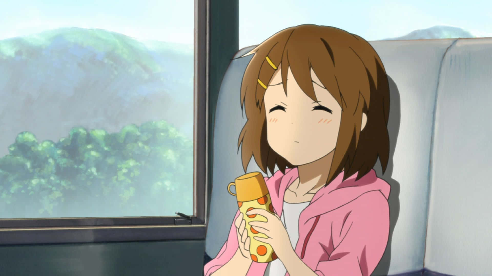 yui hirasawa 桌布 壁紙 — 一個開朗的動漫女孩，棕色頭髮，坐在窗邊，拿著一個黃色保溫瓶，微笑著看著外面綠色的山丘掠過。