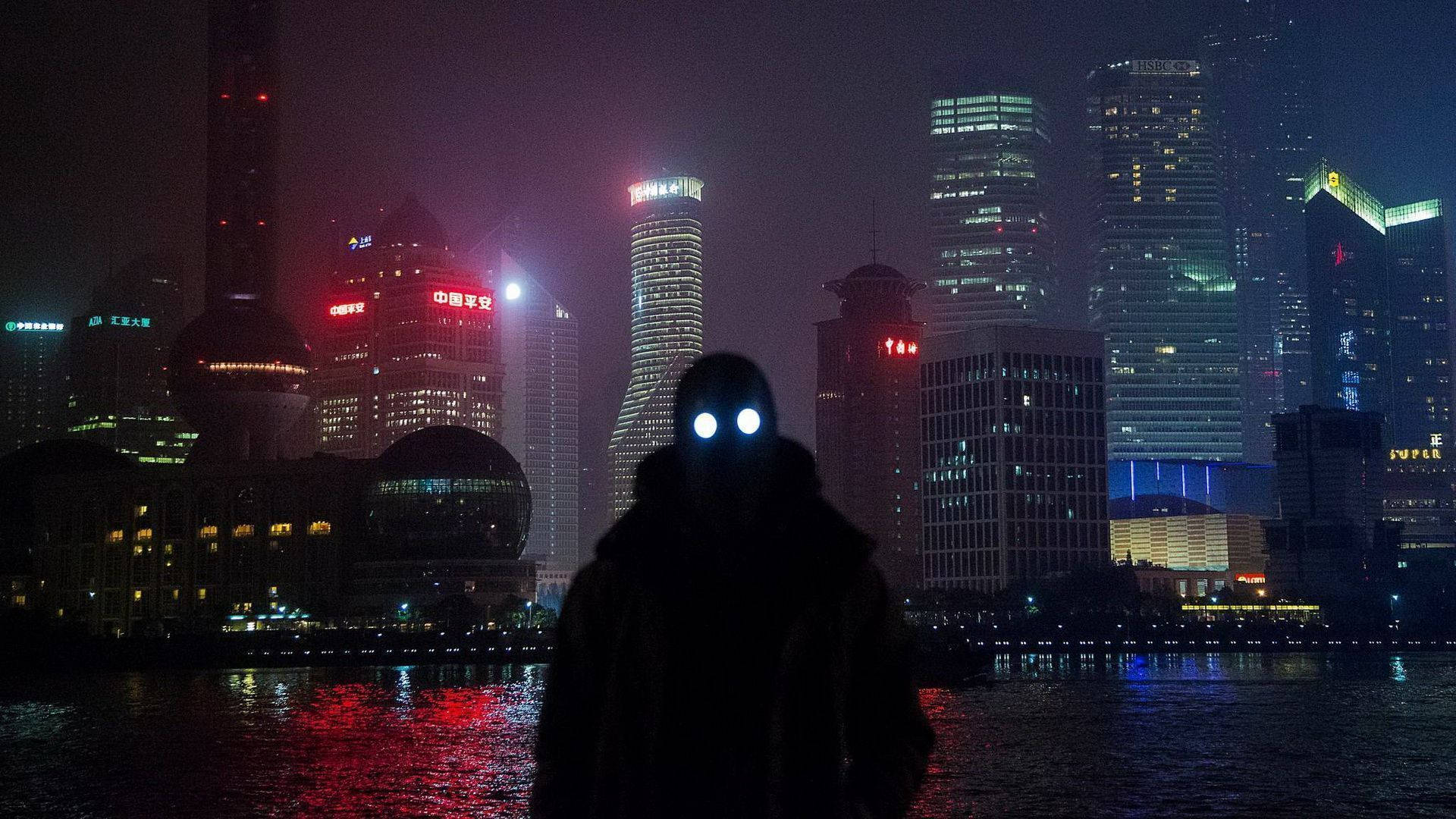 賽博龐克 桌布 壁紙 — 一個陰影人物，眼睛發光，站在夜晚霓虹燈照亮的天際線前，倒映在下面的水中。
