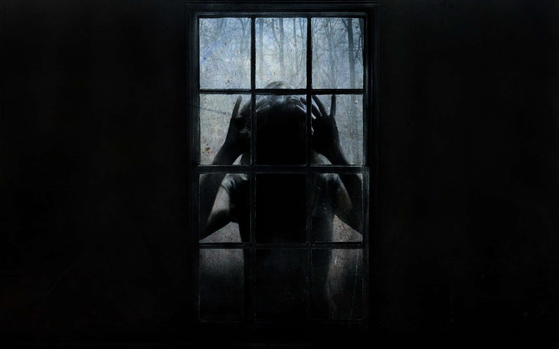 window 桌布 壁紙 — 一個陰暗的身影將雙手按在骯髒的窗玻璃上，在昏暗的房間內，以外面荒涼的樹林為背景形成剪影。