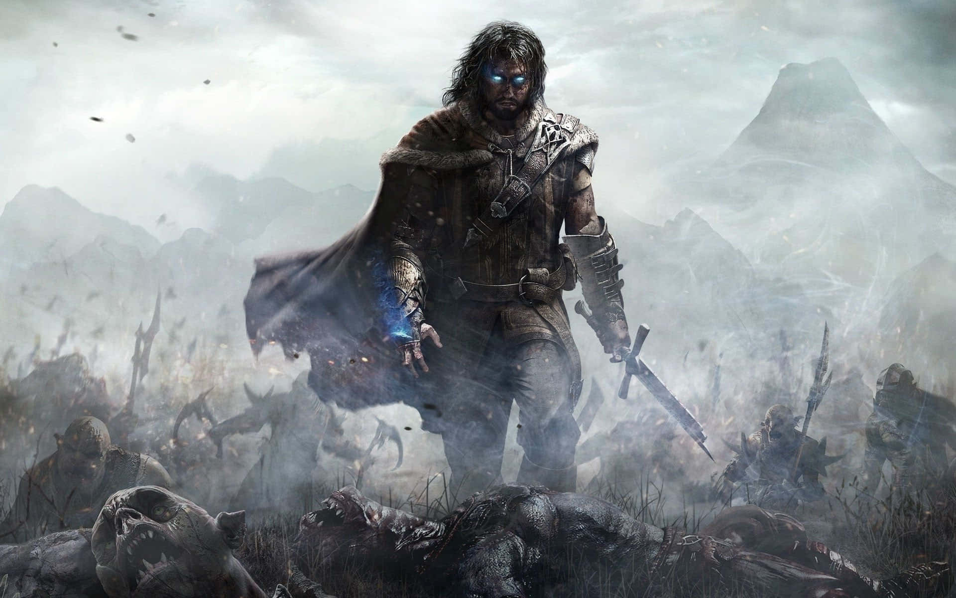 Shadow Of Mordor 桌布 壁紙 — 一個陰沉的戰士，擁有發光的藍色眼睛和一把劍，勝利地站在霧氣瀰漫的山地戰場上倒下的敵人之上。