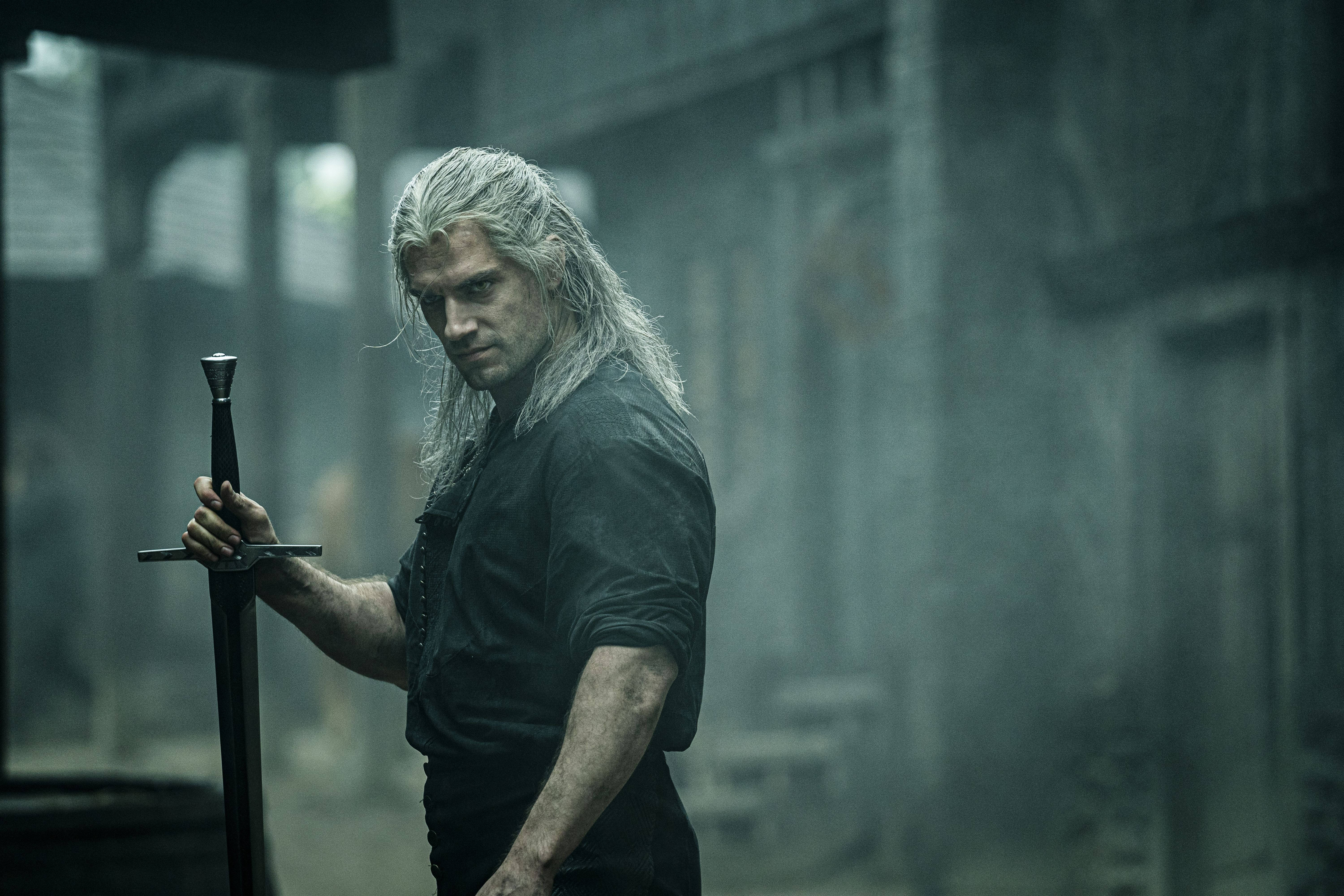 witcher 4K 桌布 壁紙 — 一個陰沉的戰士，長長的白髮，在昏暗的光線下，於迷霧的石頭廢墟中握著一把劍。