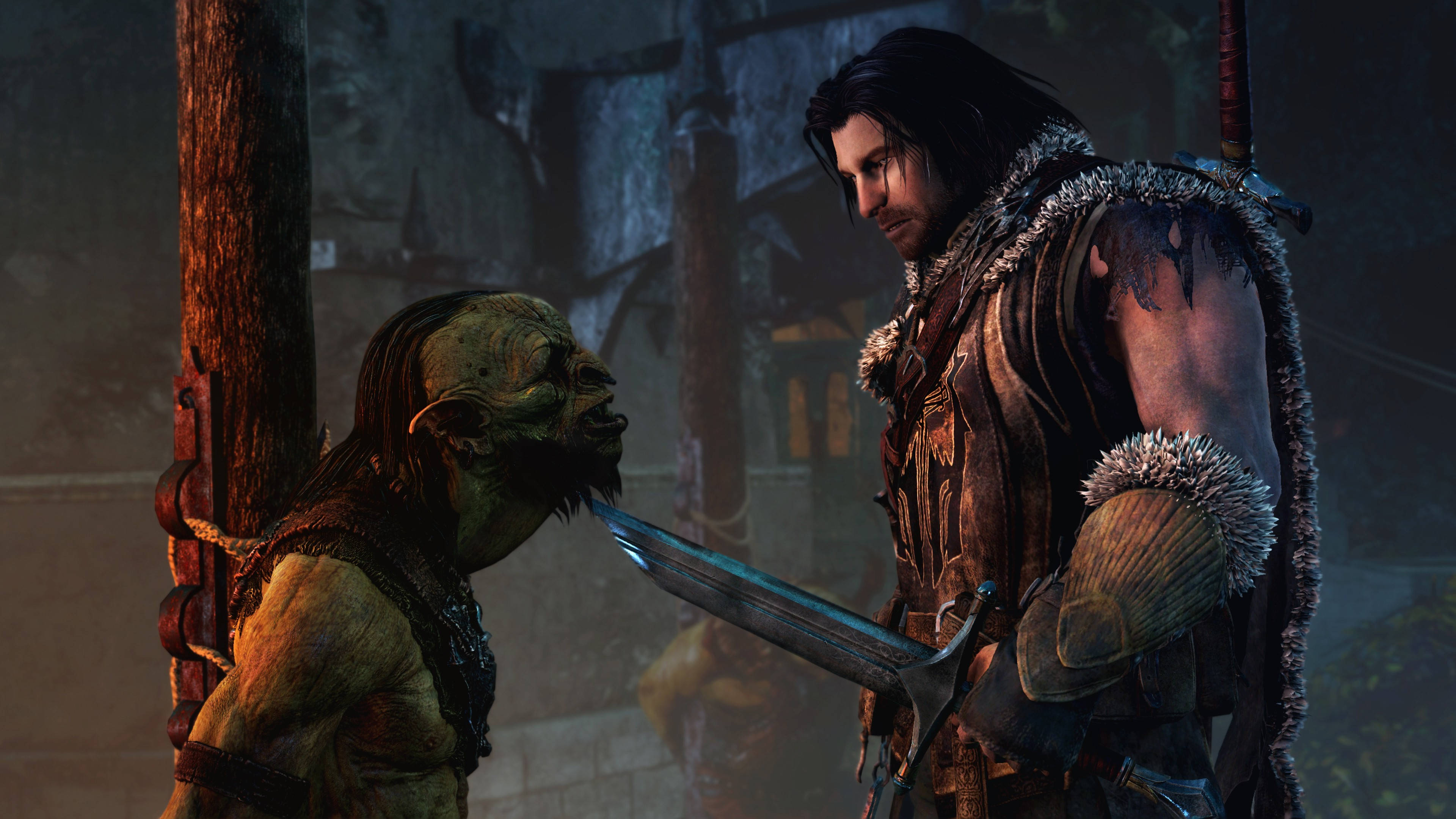 middle earth shadow of war 桌布 壁紙 — 一個陰沉的戰士手持劍，在一個光線昏暗、有石牆和木樑的地牢中面對一個被捆綁的獸人。