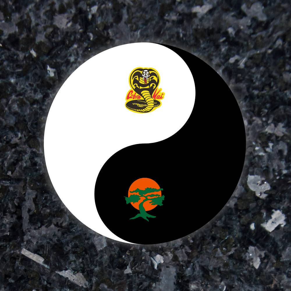 眼鏡蛇道館 桌布 壁紙 — 一個陰陽符號，白色一半有眼鏡蛇標誌，黑色一半有樹木標誌，放置在深色花崗岩表面上。