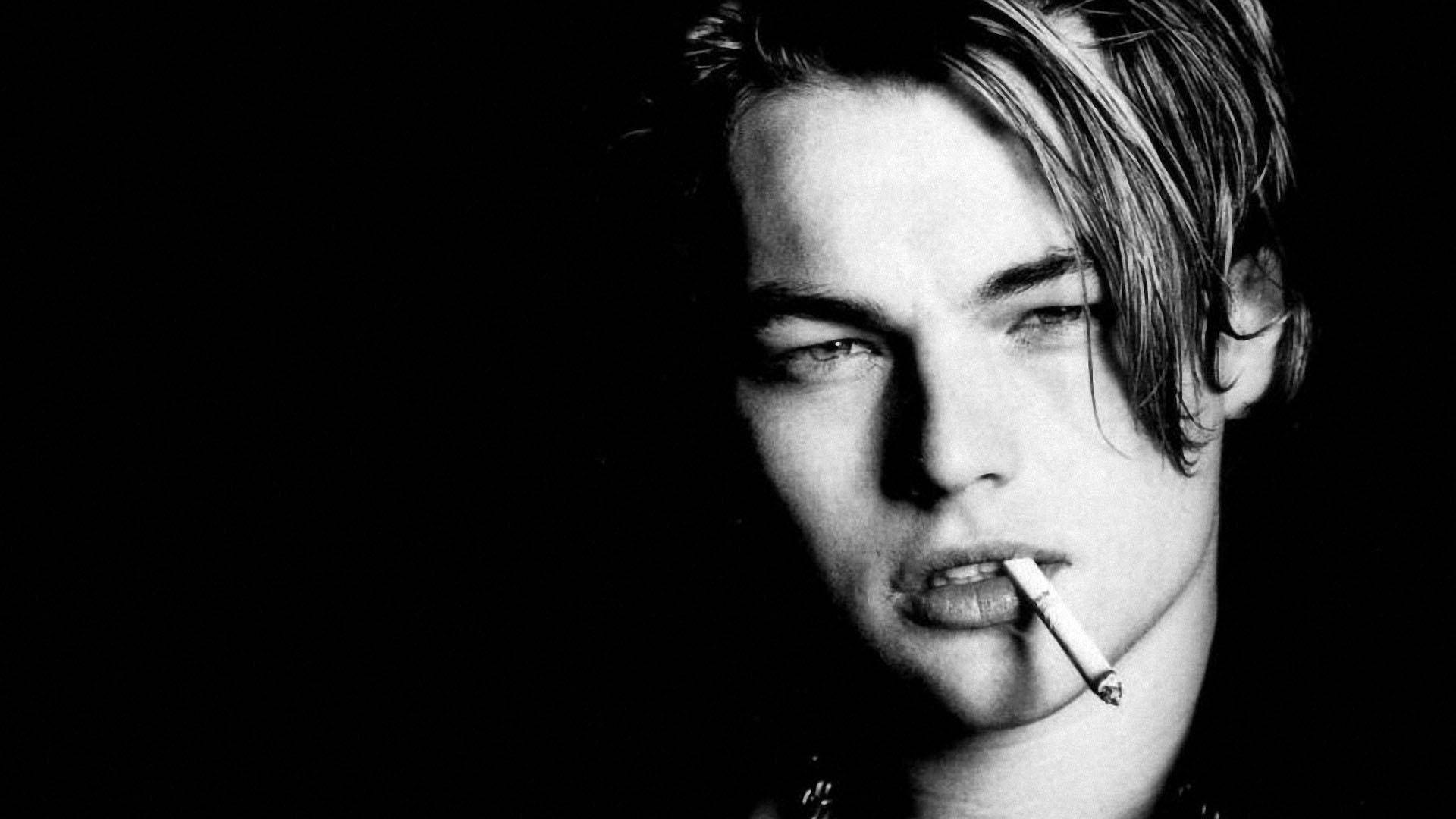 Dicaprio 桌布 壁紙 — 一個陰鬱的黑白肖像，一個年輕人口中叼著香煙，背景黑暗。