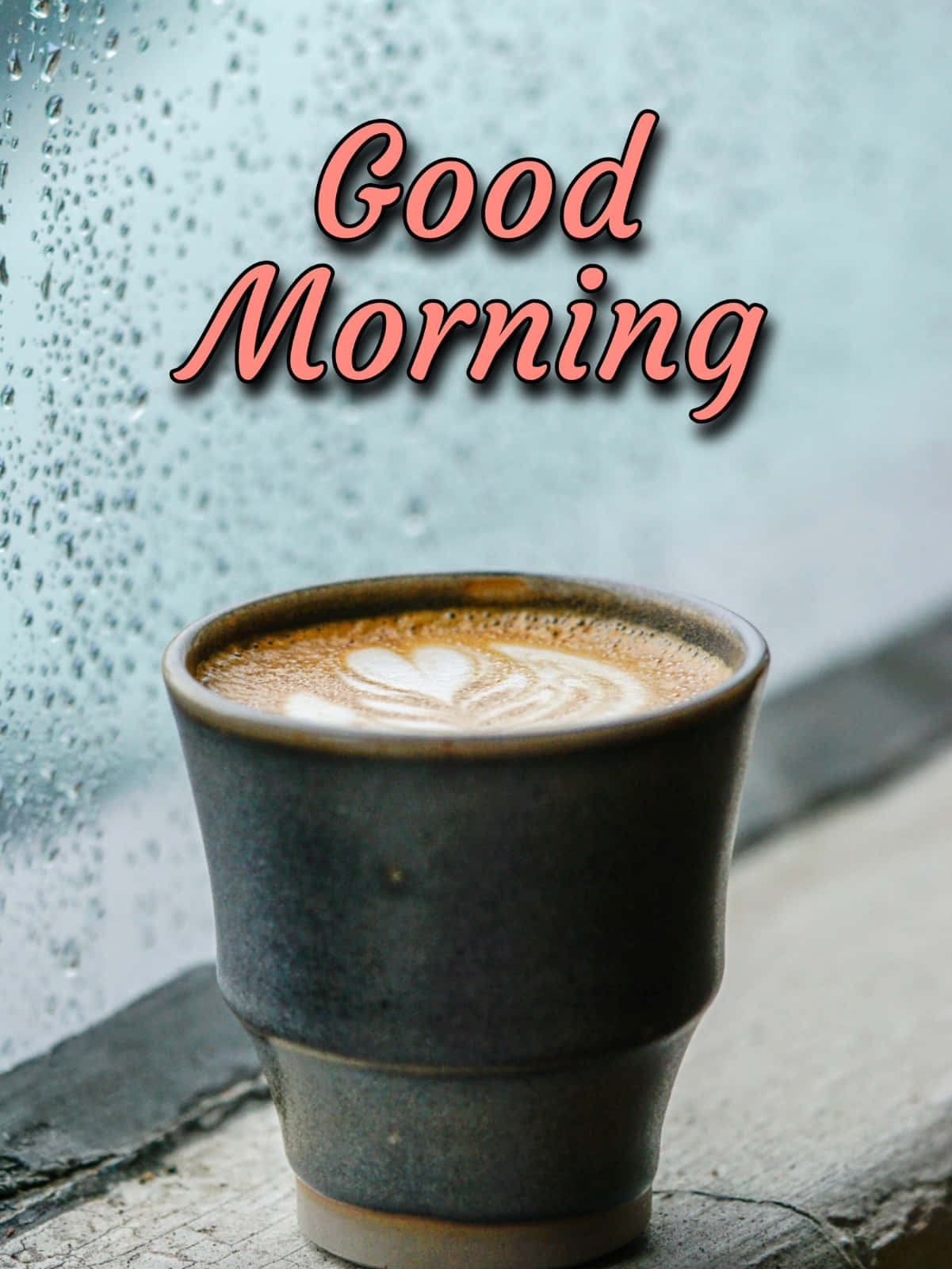 Coffee Aesthetic 桌布 壁紙 — 一個陶瓷咖啡杯，上面有心形拉花藝術，放在雨點斑駁的窗邊，並有「Good Morning」字樣。