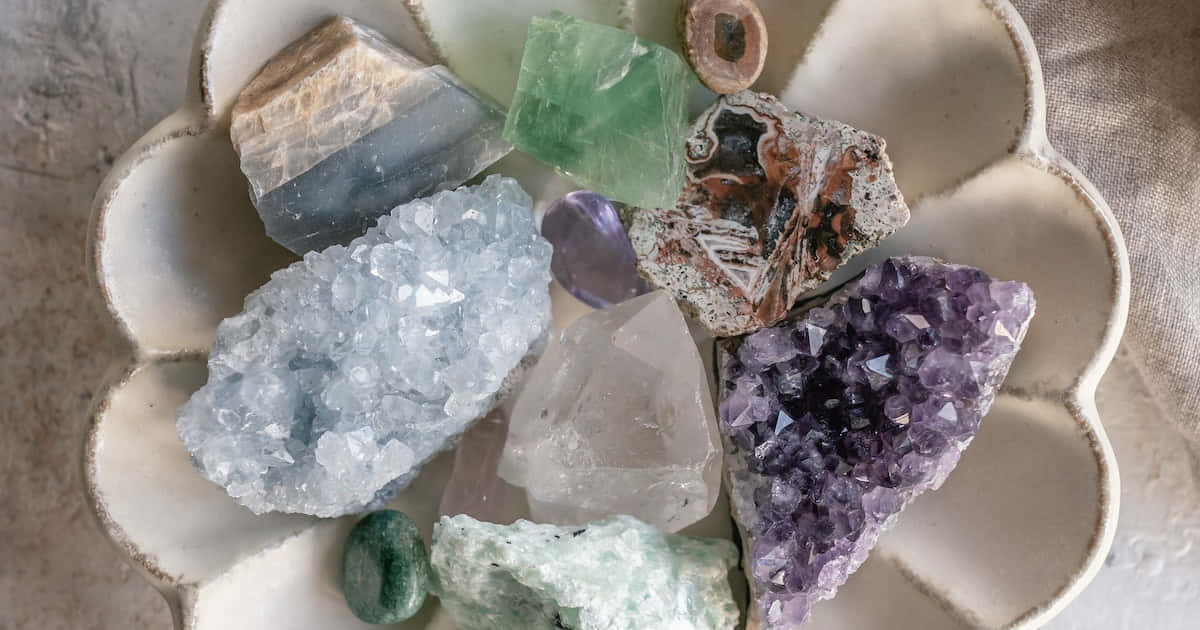 水晶 桌布 壁紙 — 一個陶瓷花形碟子盛載著色彩鮮豔的各種水晶和石頭，包括紫水晶石英和綠色螢石。