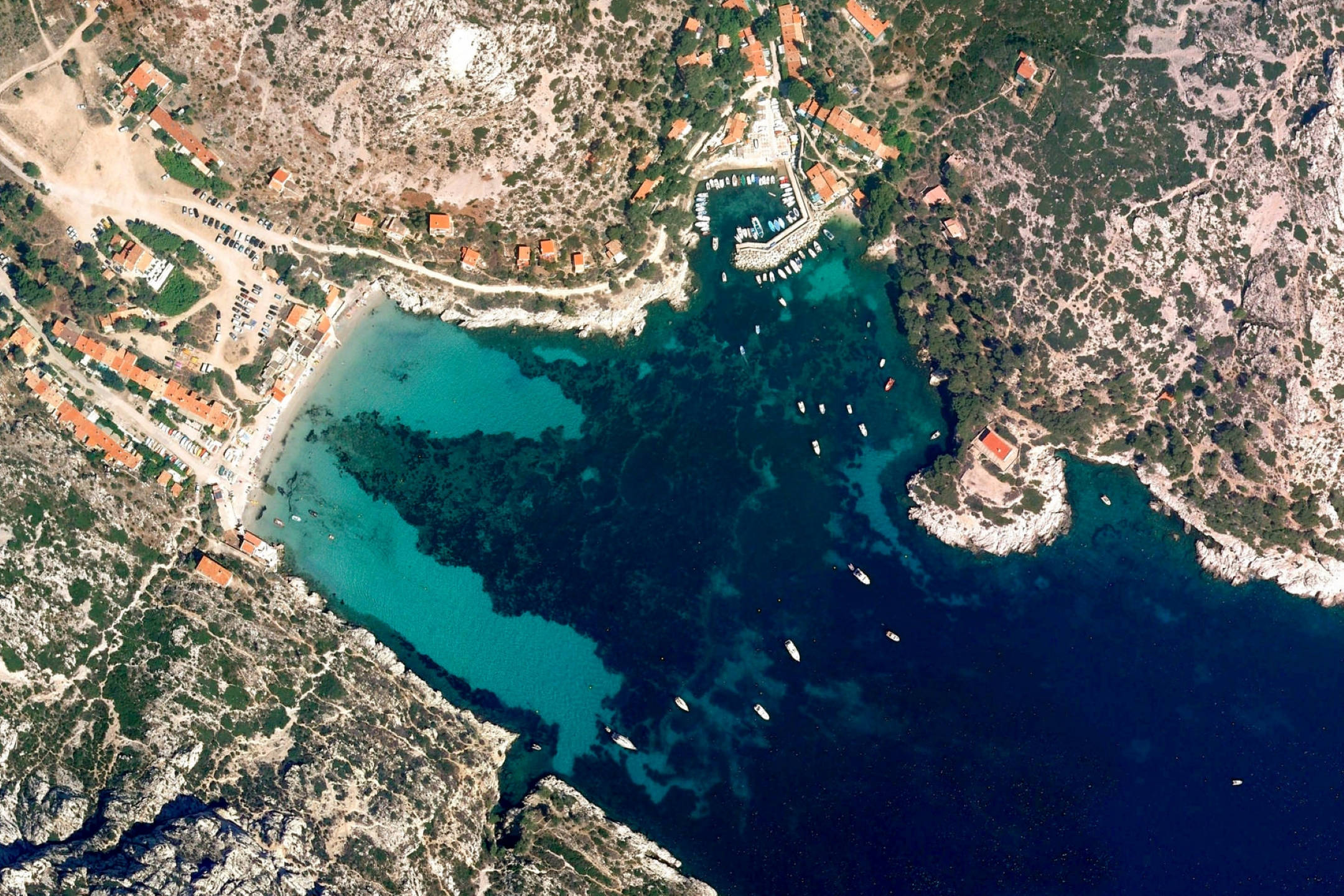 Google 地球 桌布 壁紙 — 一個隱蔽海灣的鳥瞰圖，碧綠海水，船隻停泊在靠近陶土屋頂房屋附近，這些房屋坐落在崎嶇的綠色山丘中。