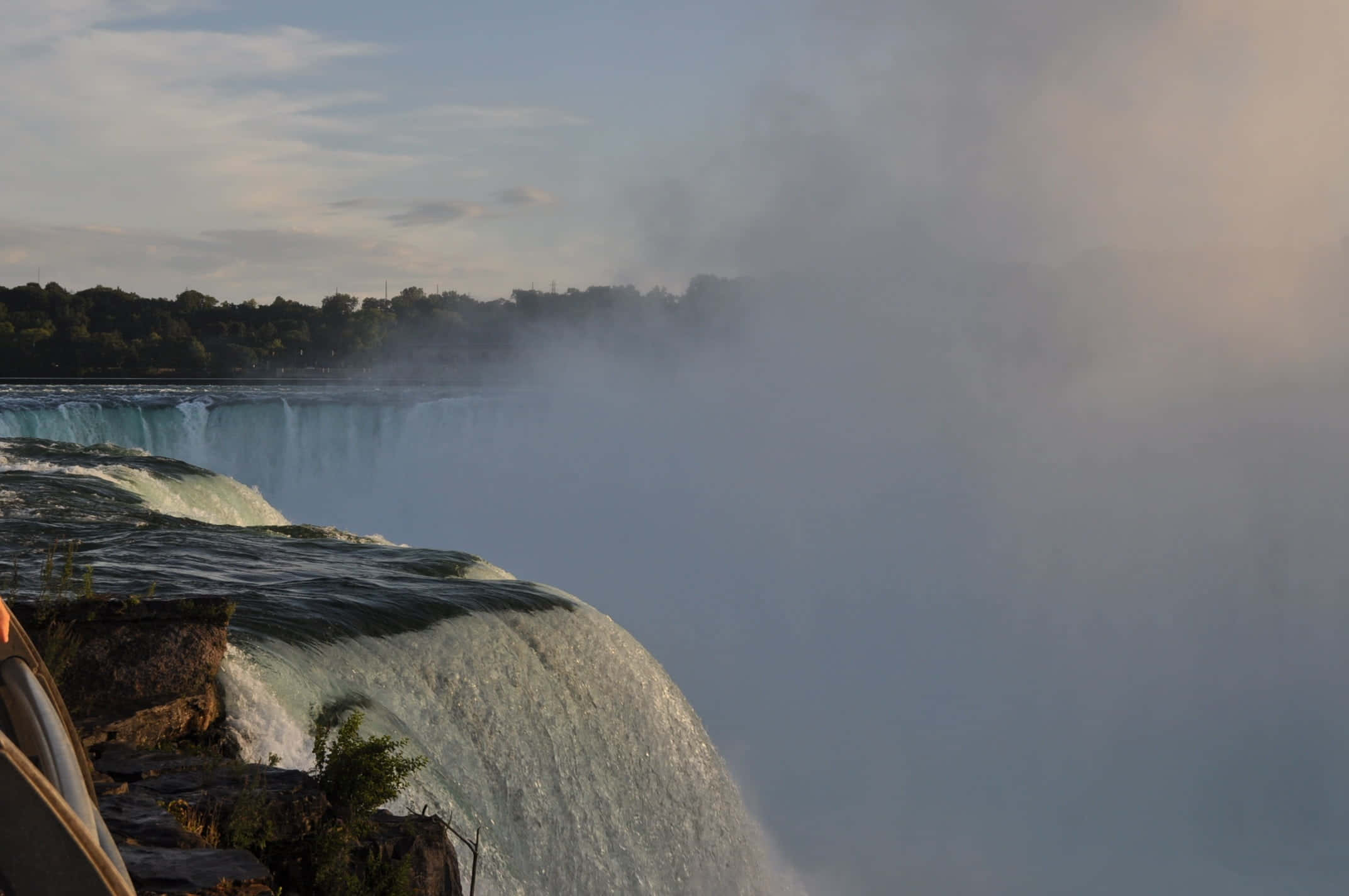 720p Niagara Falls 桌布 壁紙 — 一個雄偉的瀑布從岩石懸崖上強力傾瀉而下，在柔和的天空下形成一層薄霧。