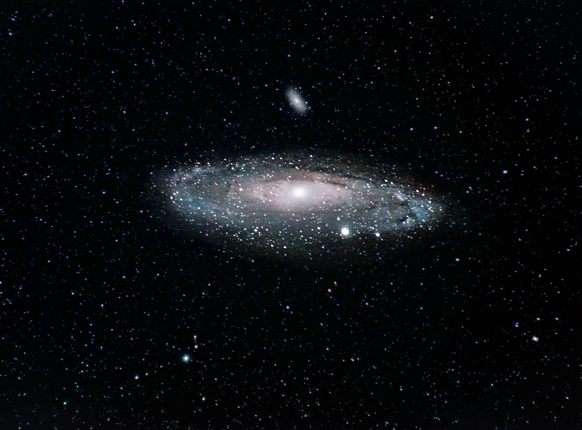 Stars 桌布 壁紙 — 一個雄偉的螺旋星系，帶有發光的旋臂和明亮的核心，主宰著一個充滿恆星的宇宙虛空。