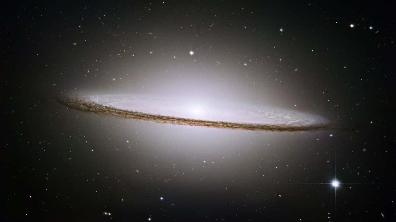 Sombrero Galaxy 桌布 壁紙 — 一個雄偉的螺旋星系在黑暗的宇宙背景下閃耀著明亮的恆星和旋轉的塵埃帶。