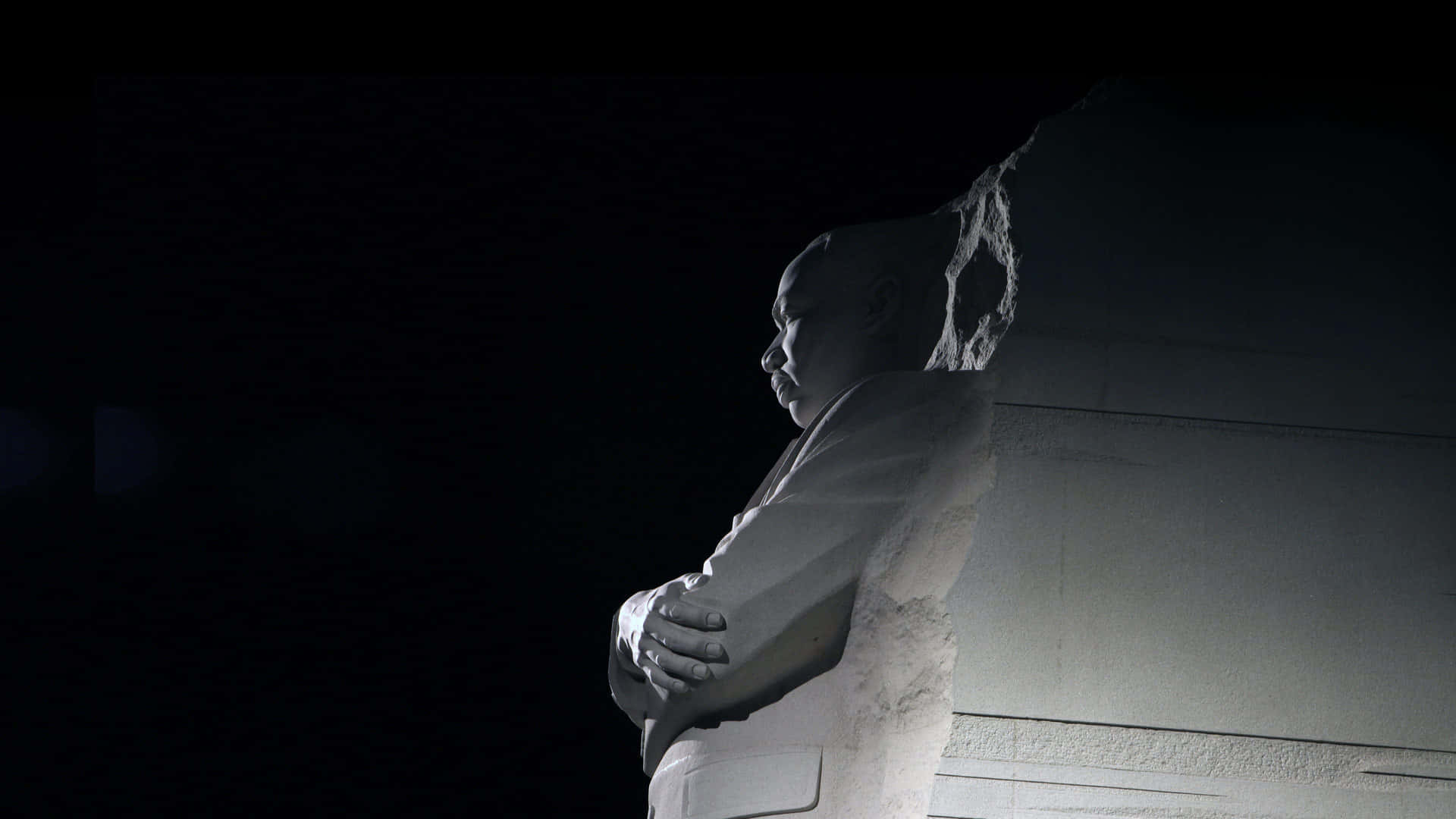 Statue Aesthetic 桌布 壁紙 — 一個雙手交叉的男人的莊嚴石像，在漆黑的夜空下形成鮮明對比。