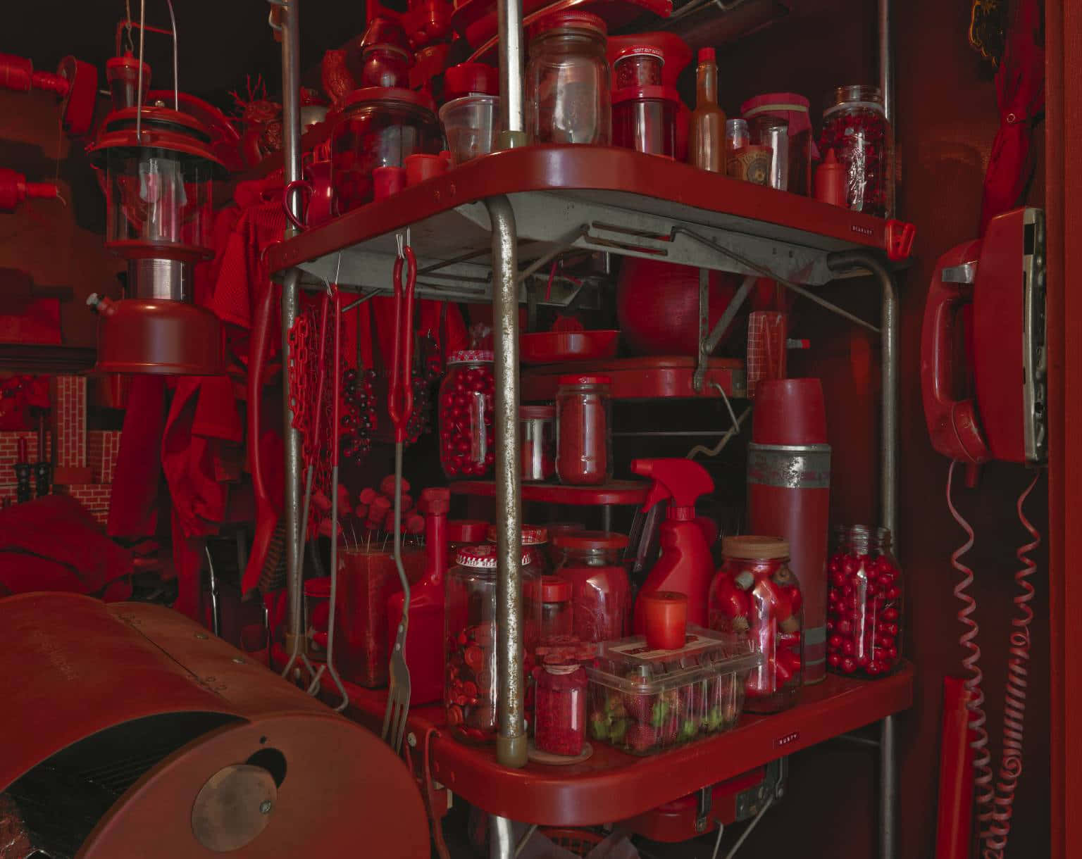 Red Room 桌布 壁紙 — 一個雜亂的紅色主題儲物角落，充滿了罐子、瓶子、工具和復古物品，沐浴在深紅色的光線中。