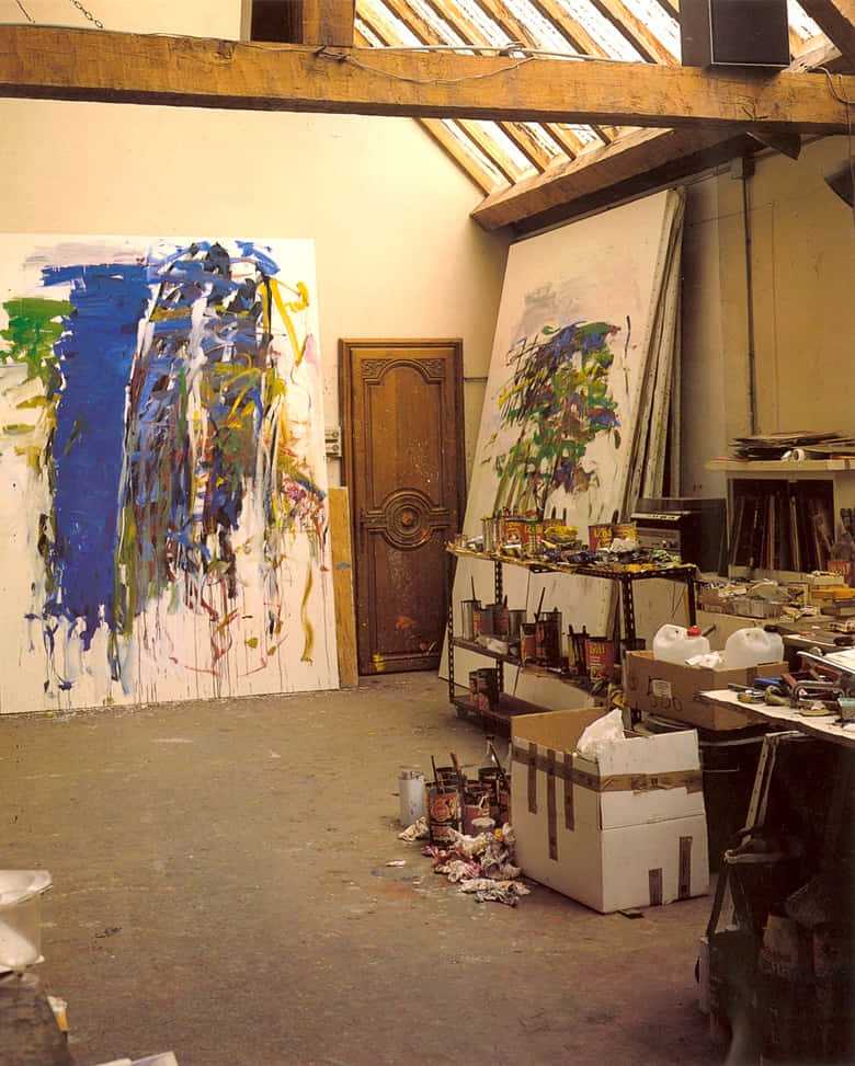 Painting 桌布 壁紙 — 一個雜亂的藝術家工作室，大型抽象畫靠牆擺放，藝術用品散落在木樑天花板下。