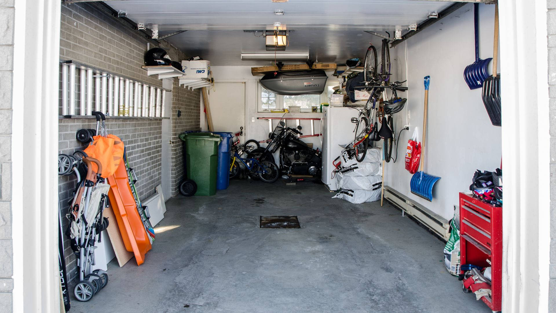 room 桌布 壁紙 — 一個雜亂的車庫，在明亮的日光下堆滿了腳踏車、工具和儲物箱。