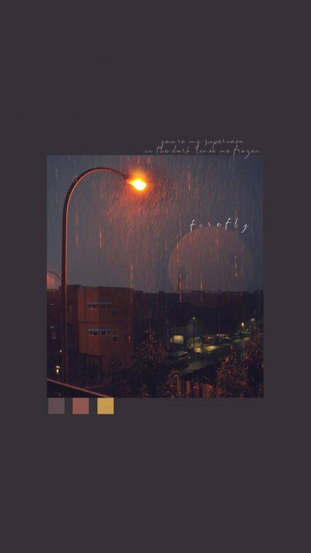 美學平板 桌布 壁紙 — 一個雨夜的街景，由溫暖發光的路燈照亮，燈光投射在落下的雨滴和遠處的建築物上。