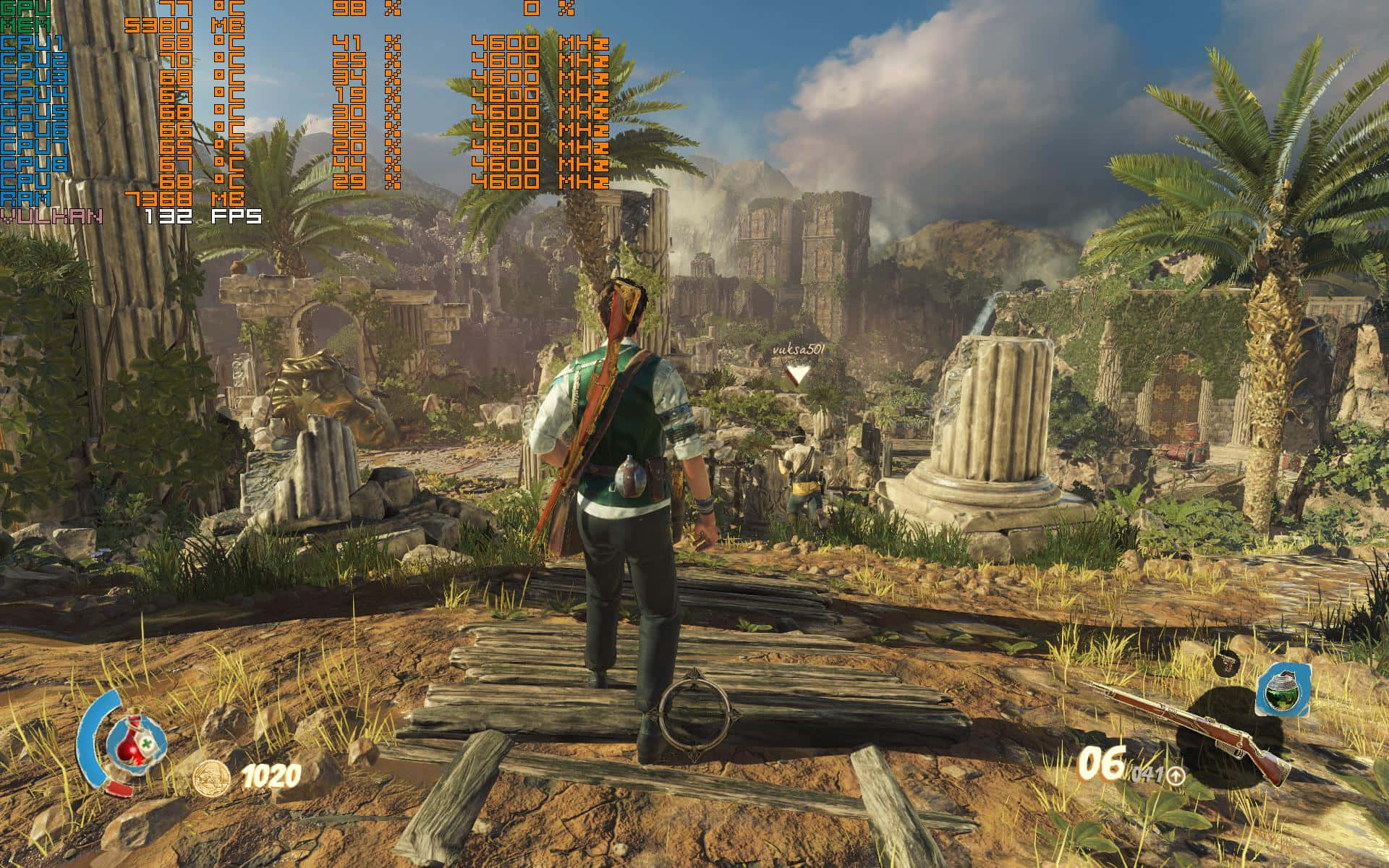 1920x1080 Strange Brigade 桌布 壁紙 — 一個電子遊戲角色站在木橋上，俯瞰被棕櫚樹和遠山環繞的古代遺跡，天空局部多雲。