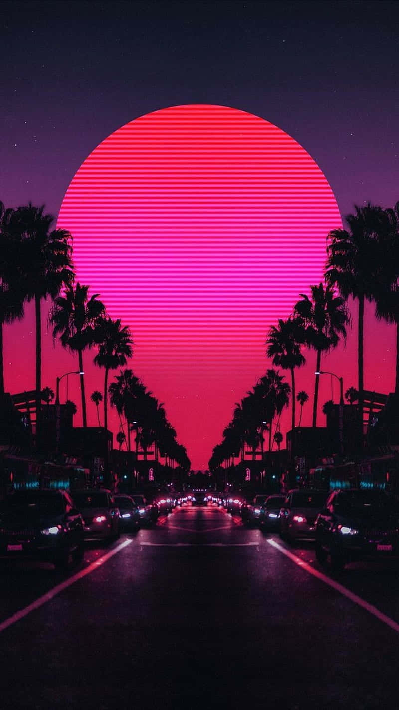Pink Sunset iPhone 桌布 壁紙 — 一個霓虹粉紅和洋紅色的條紋太陽在夜晚籠罩著一條棕櫚樹成蔭的街道，有汽車和發光的燈光。