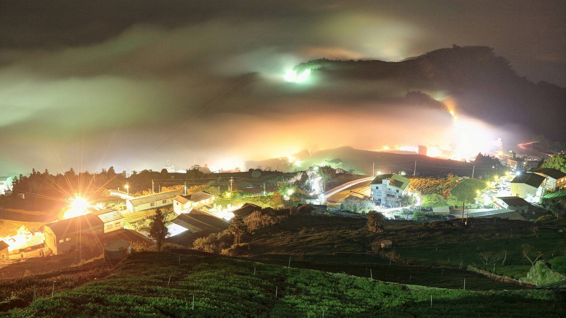 一個舒適的山村夜景，燈光閃爍，山巒霧繞。