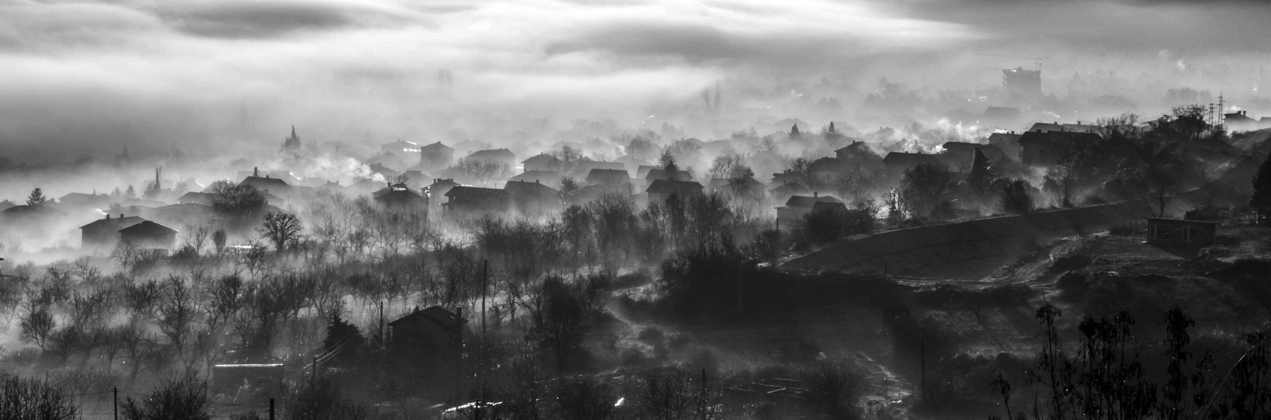 Bulgaria 桌布 壁紙 — 一個霧氣瀰漫的黑白全景，展現一個沉睡的村莊坐落在起伏的丘陵中，天空多雲。